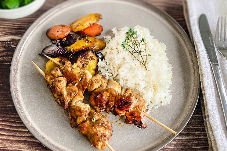 Hühnerspieße mit Reis und Miso-Karotten, angerichtet auf einem Teller