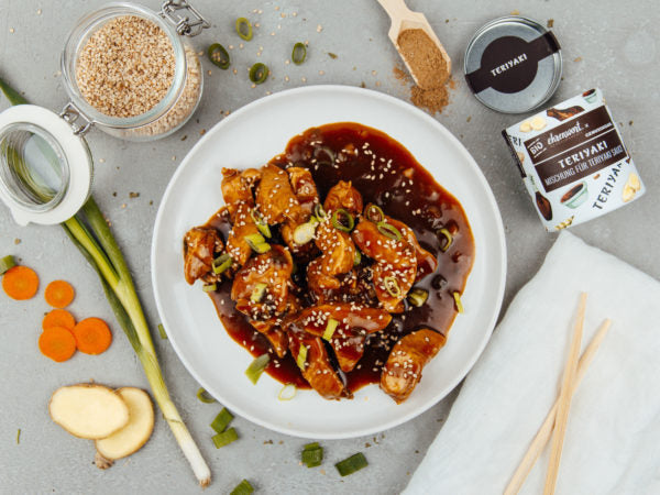 Saftiges Teriyaki-Chicken auf Teller serviert. Goldbraun glasiert, garniert mit Sesam und Frühlingszwiebeln, angerichtet mit Gemüse, regional & nachhaltig.